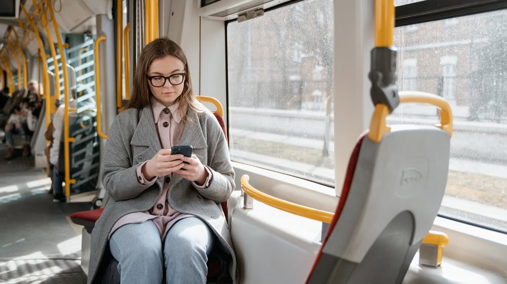 mobilní signál ve vlaku, cestující s telefonem u okna